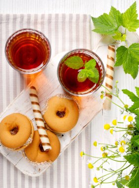 Beyaz ahşap masada lezzetli kurabiyelerle iki fincan sıcak çay. Üst görünüm düz grup nesneleri