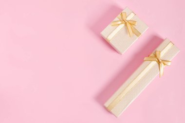 Pembe kağıt arka planda tebrik etmek için altın hediye kutuları. Üst görünüm, düz görünüm, boşluk konseptini kopyala.