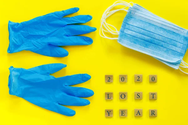 蓝色医用手套和口罩在纸黄色背景上 并附有概念性文字 2020年失去的岁月 用于设计 — 图库照片