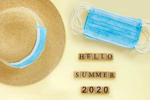 藁帽子と青い医療用マスクと紙ベージュの背景 コンセプトテキスト デザインのための Hello Summer 2020 — ストック写真