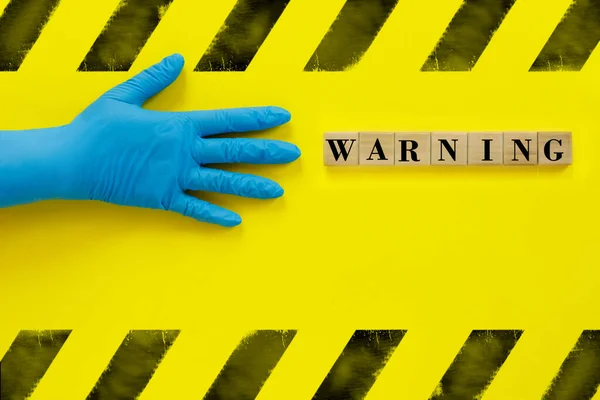 Χέρι Μπλε Ιατρικό Γάντι Και Επιγραφή Ξύλινους Κύβους Προειδοποίηση Κίτρινο — Φωτογραφία Αρχείου