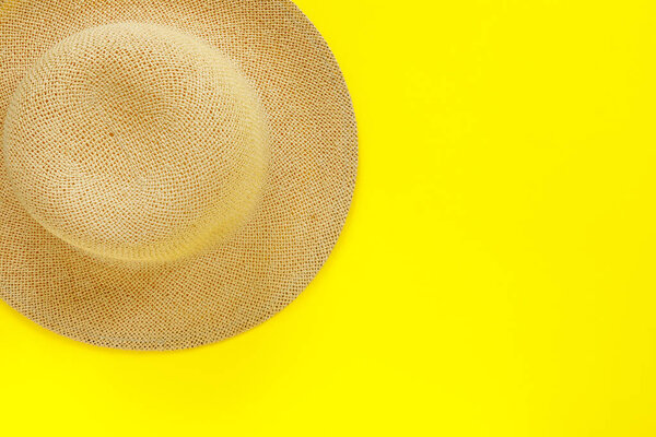 Fashionable straw hat on yellow paper background