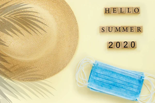 藁帽子と青い医療用マスクと紙ベージュの背景 コンセプトテキスト デザインのための Hello Summer 2020 — ストック写真