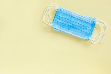 Mavi tıbbi eldiven ve kağıt bej arka planda maske. Koronavirüs salgını. Düz konum, üst görünüm, uzay konseptini kopyala.