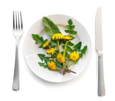 Bouquet of beautiful yellow dandelions on plate. Salad on  white isolated background. Flat lay, top view, copy space concept. clipart