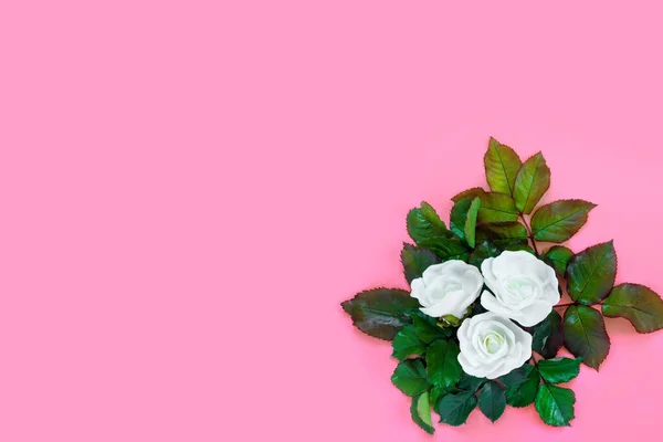 ピンクの紙の背景に白いバラと緑の葉の美しい花束 創作グリーティングカード — ストック写真