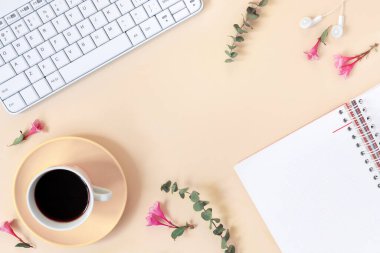 Üst kattaki ofis masası, dizüstü bilgisayarı, defteri, kulaklığı, okaliptüsü ve sarı kağıttan arka planı olan..