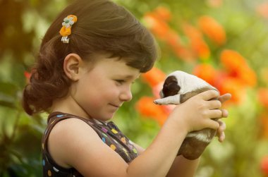 Dört yıl yaşlı kız bahçede köpek yavrusu ile oynarken