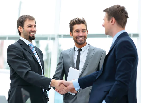 Зрелый бизнесмен пожимает руку, чтобы заключить сделку со своим партнером и коллегами в современном офисе — стоковое фото