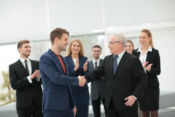 Two cheerful business people shaking hands while their colleague — Stock Photo, Image