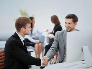 Ofiste otururken el sıkışan iki mutlu genç adam