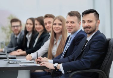 Kendine güvenen işadamı meslektaşları arasında kamera bakıyor