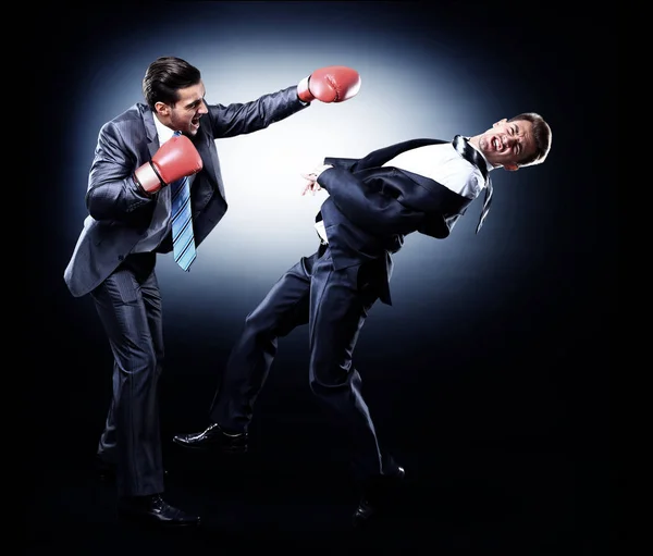 Two young businessman boxing againts dark background — Stock Photo, Image