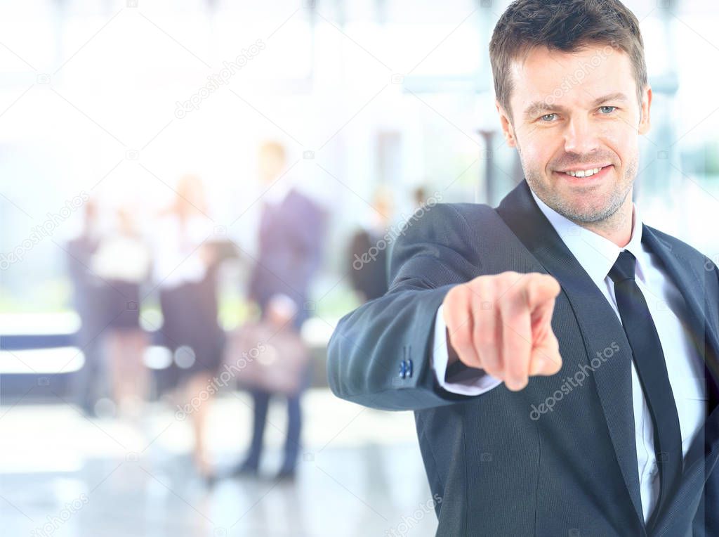 Portrait of smiling mature business man pointing at you in office