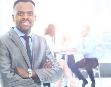 arka planda çalışan yöneticiler ile Afrika kökenli Amerikalı iş adamı gülümseyen portresi