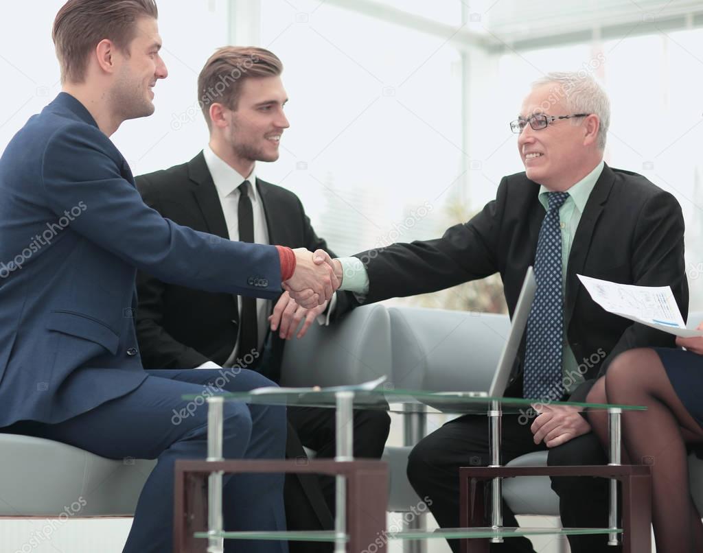 Handshake between businesspeople in a stylish office  in the bac