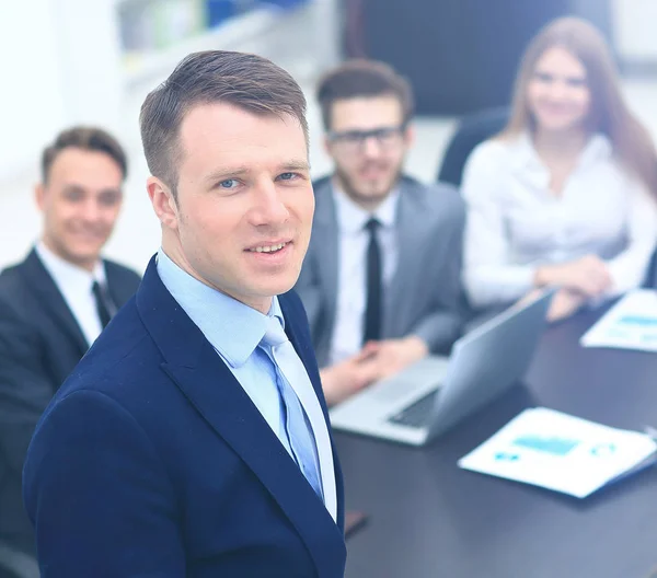 Joven empresario mirando a la cámara en el fondo de su equipo — Foto de Stock