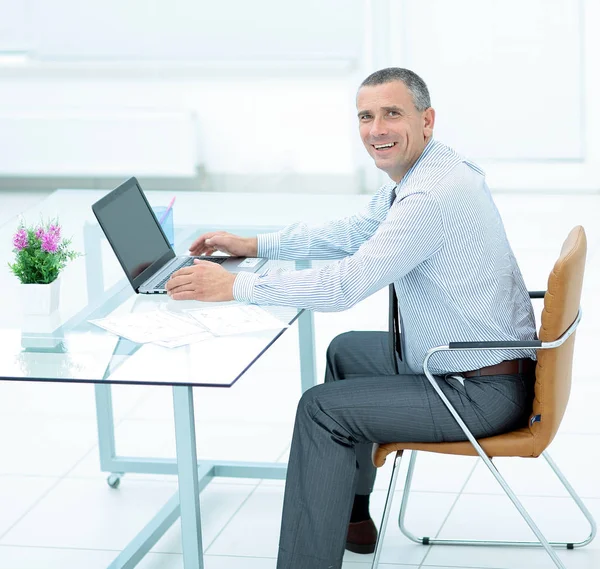 Framgångsrik leende affärsman arbetar på laptop på skrivbord i offi — Stockfoto