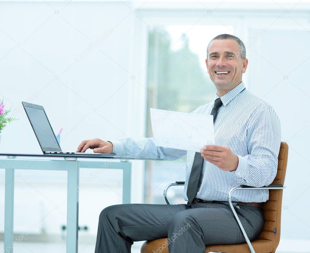 successful smiling businessman with documents is sitting on the