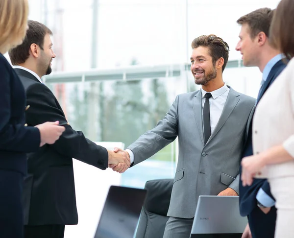 Homem de negócios maduro apertando as mãos para selar um acordo com seu parceiro e colegas em um escritório moderno — Fotografia de Stock