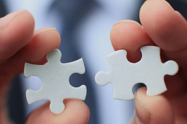 Empresário segurando duas peças brancas em branco nas mãos conceitual de resolver um problema, crescimento e desenvolvimento . — Fotografia de Stock