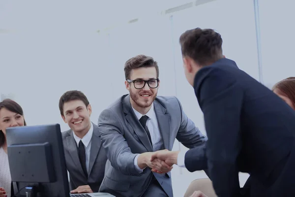 Dois empresários confiantes apertando a mão e sorrindo enquanto se sentam à mesa junto com seus colegas — Fotografia de Stock