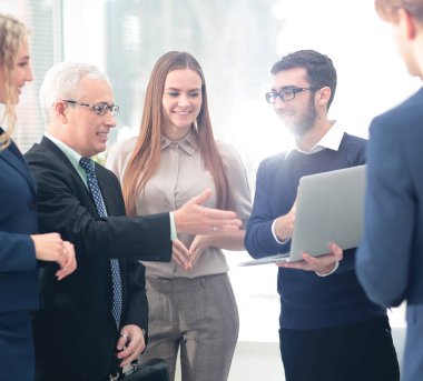 bir dizüstü bilgisayar ve iş ekibi ile gülümseyen olgun Yöneticisi