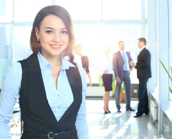 Porträtt av en karismatisk kvinna vid ett möte medan hennes team som arbetar i bakgrunden — Stockfoto