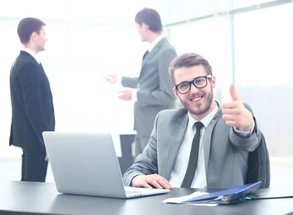Handsome young business man with people in background at office meeting. showing thumbs up Stock Image