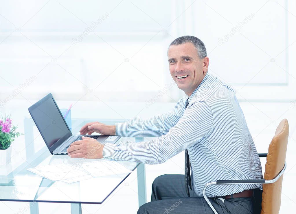 successful smiling businessman working on laptop at Desk in offi