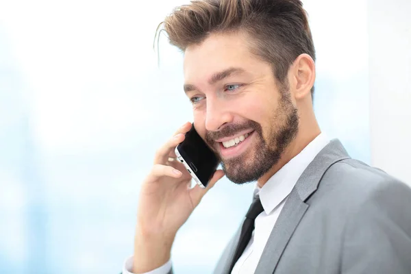 Hombre de negocios guapo en una oficina con teléfono inteligente — Foto de Stock