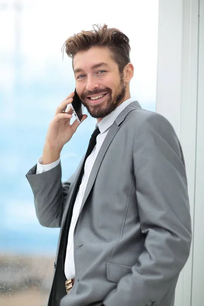 Bonito homem de negócios em um escritório usando smartphone — Fotografia de Stock