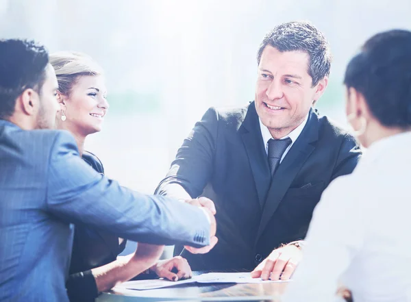 Зрілий бізнесмен потискає руки, щоб запечатати угоду зі своїм партнером і колегами в сучасному офісі — стокове фото