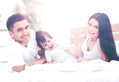 Küçük çocuklu bir aile yatak odasında yatıyor.