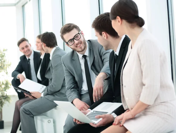 Colegas con el ordenador portátil y papeles sentarse y hablar en el vestíbulo befo — Foto de Stock