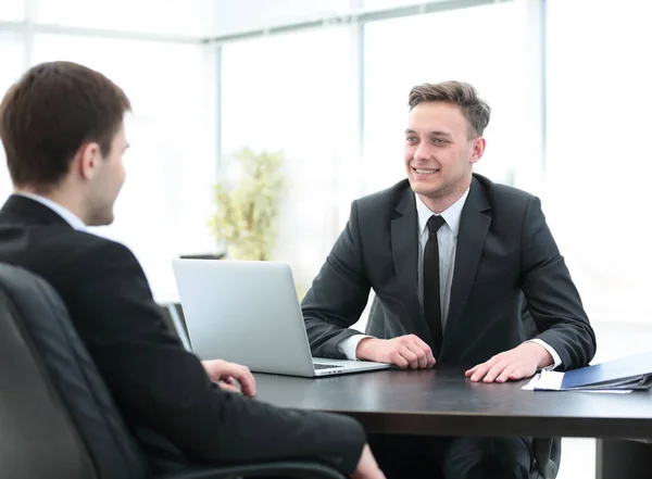 El gerente se sienta detrás del escritorio y habla con el cliente — Foto de Stock