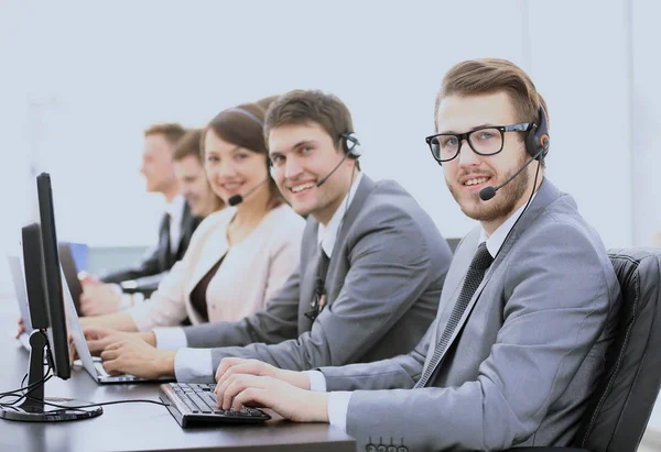 Assistentes experientes com um fone de ouvido na frente de computadores em t — Fotografia de Stock