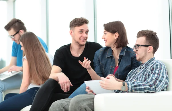 Pareja de estudiantes universitarios sentados en un sofá con amigos en — Foto de Stock