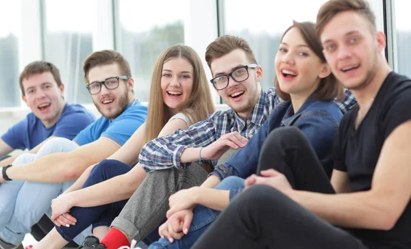 Un grupo de estudiantes felices sentados en un alféizar de la ventana y sonriendo —  Fotos de Stock