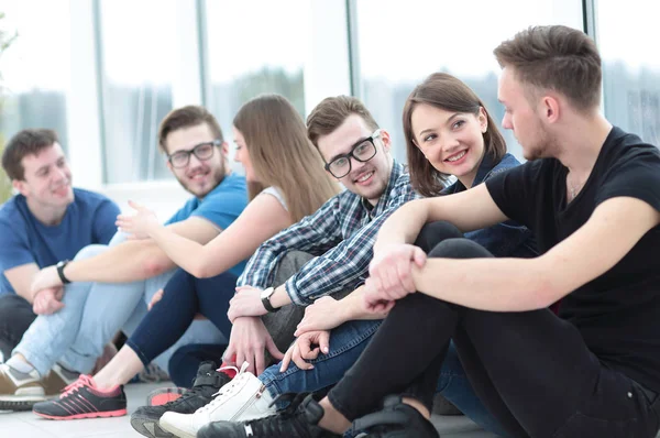 Um grupo de estudantes felizes sentados em um peitoril da janela e sorrindo — Fotografia de Stock