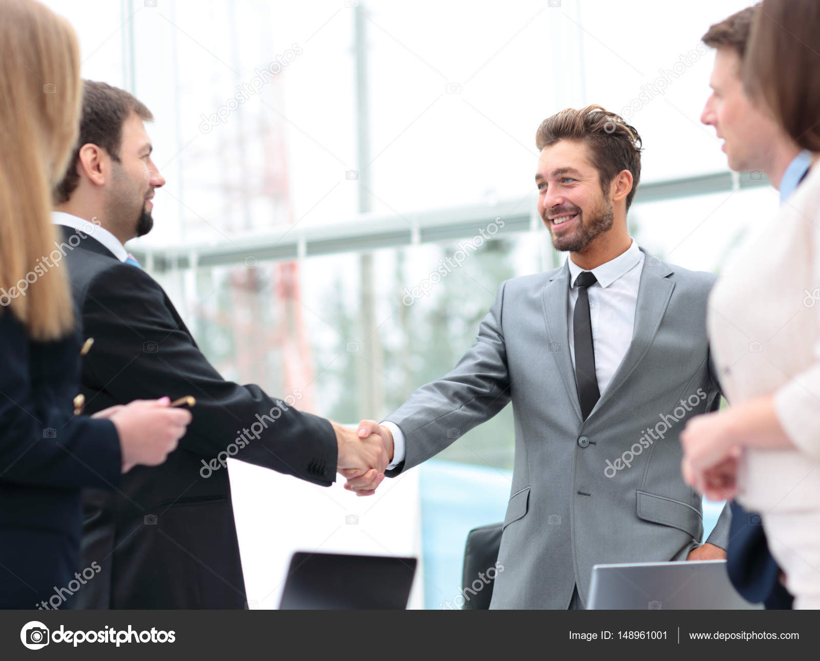 Two Business People Shaking Hands At The Business Meeting With T