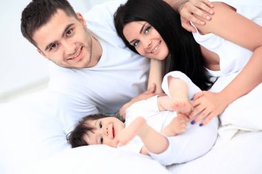 Küçük çocuklu bir aile yatak odasında yatıyor.