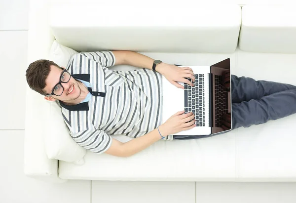 Homem relaxante no sofá com computador portátil — Fotografia de Stock