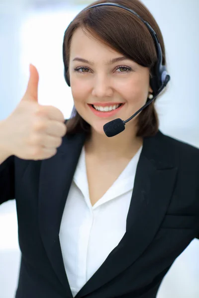 Hermosa mujer que trabaja en el centro de llamadas, usando auriculares que muestran thu — Foto de Stock