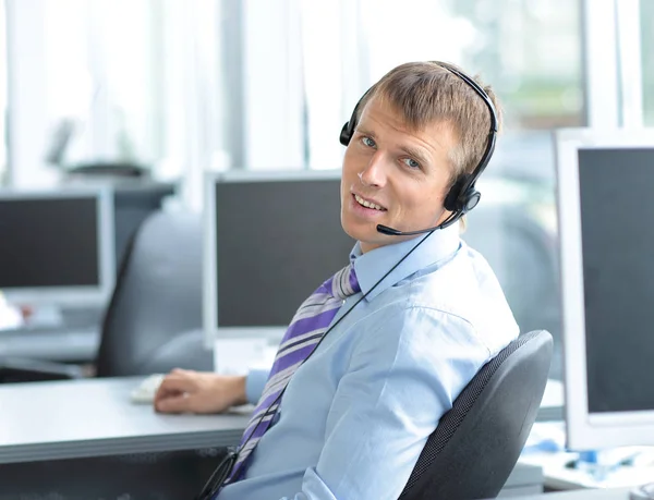 Empresario usando auriculares y sonriendo en la oficina — Foto de Stock