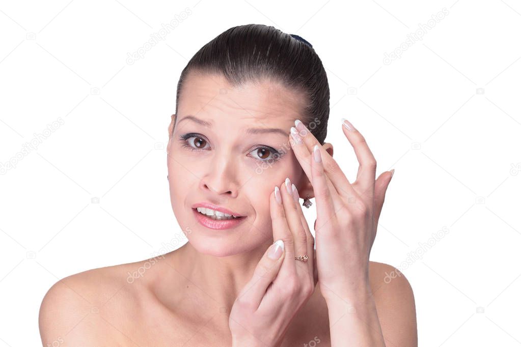 Young girl examining her face and wrinkles that can appear isola
