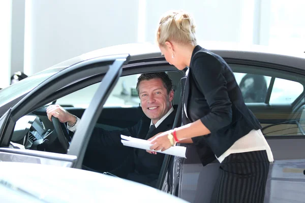 Handsome mature man buying a car at dealership — Stock Photo, Image