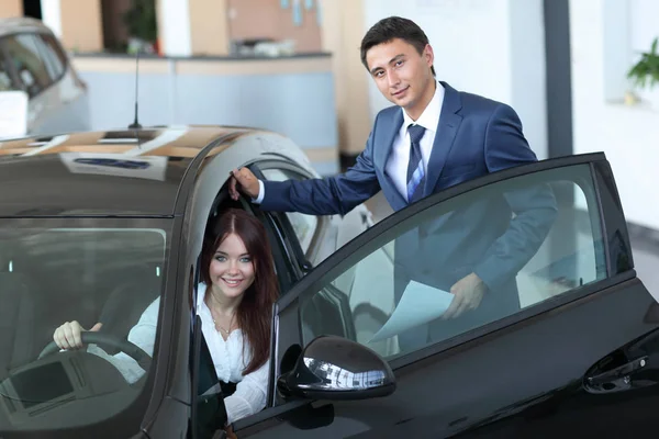 Giovane signora che sceglie nuova auto per l'acquisto in negozio di concessionaria — Foto Stock