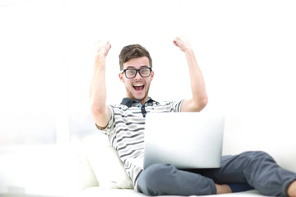 Joven feliz usando su portátil en la sala de estar luminosa . — Foto de Stock