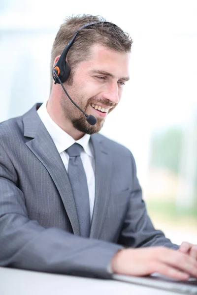 Retrato de un hombre de negocios que trabaja en su escritorio con auriculares y — Foto de Stock